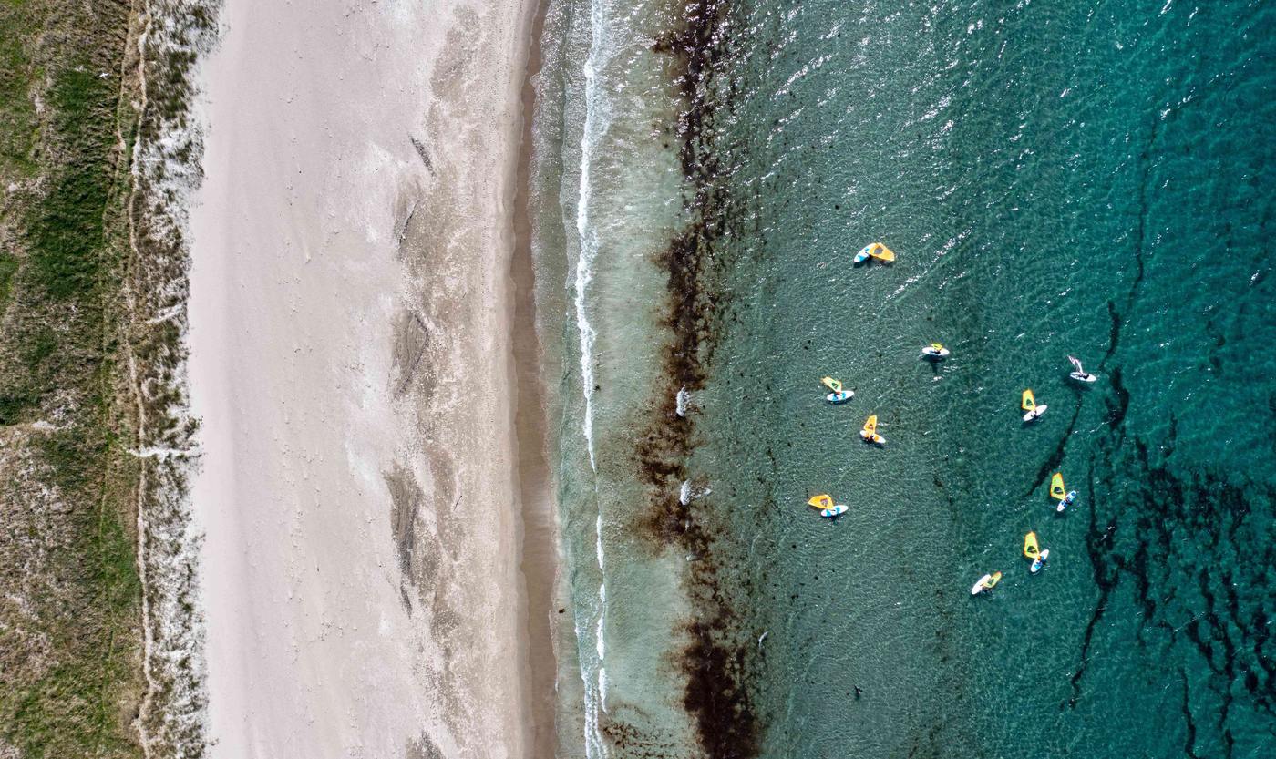 Drone-bilde av vindsurfere på turkist hav ved Lista
