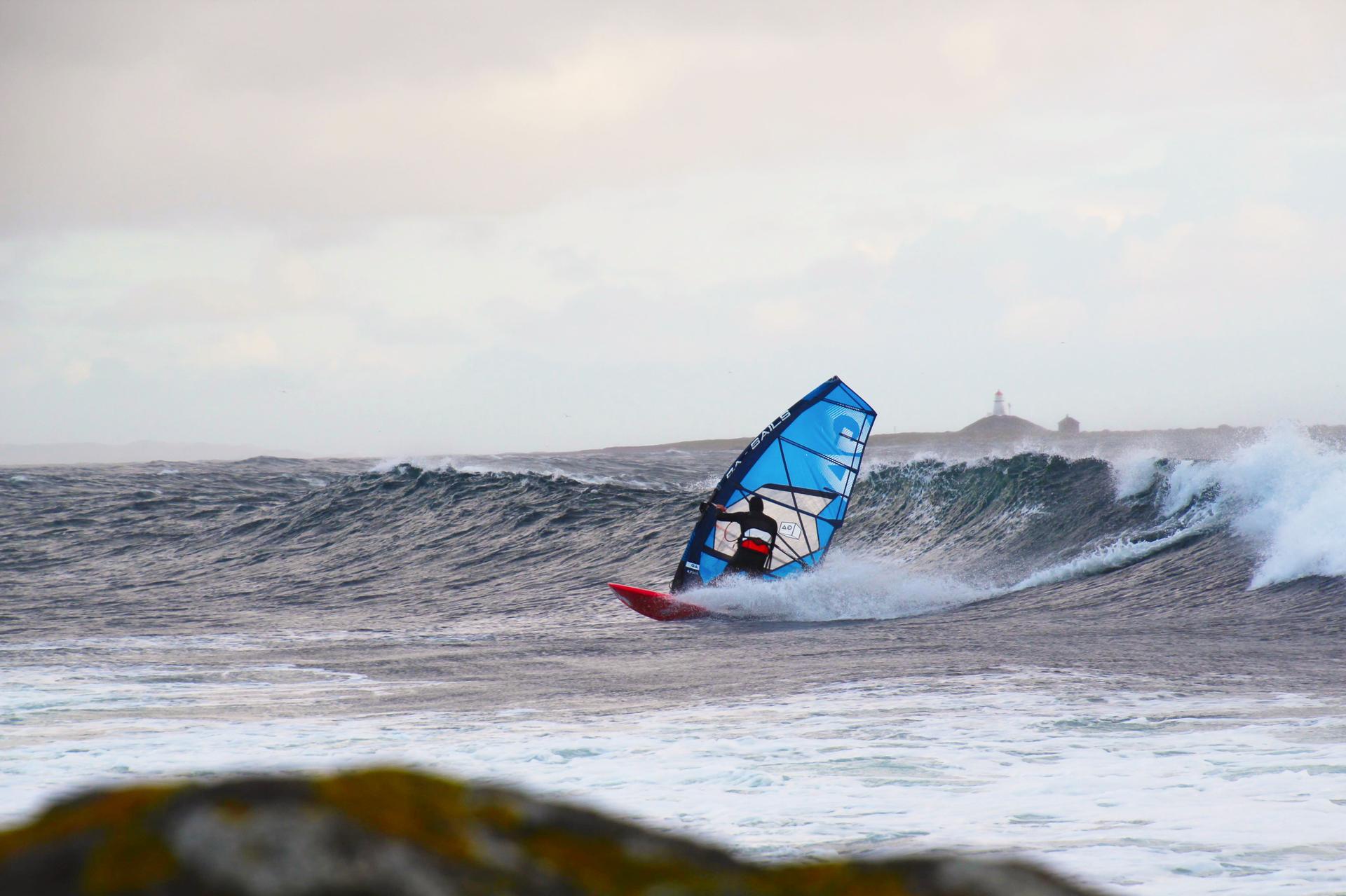 Windsurfer i bølger på Lista, med fyret i bakgrunnen